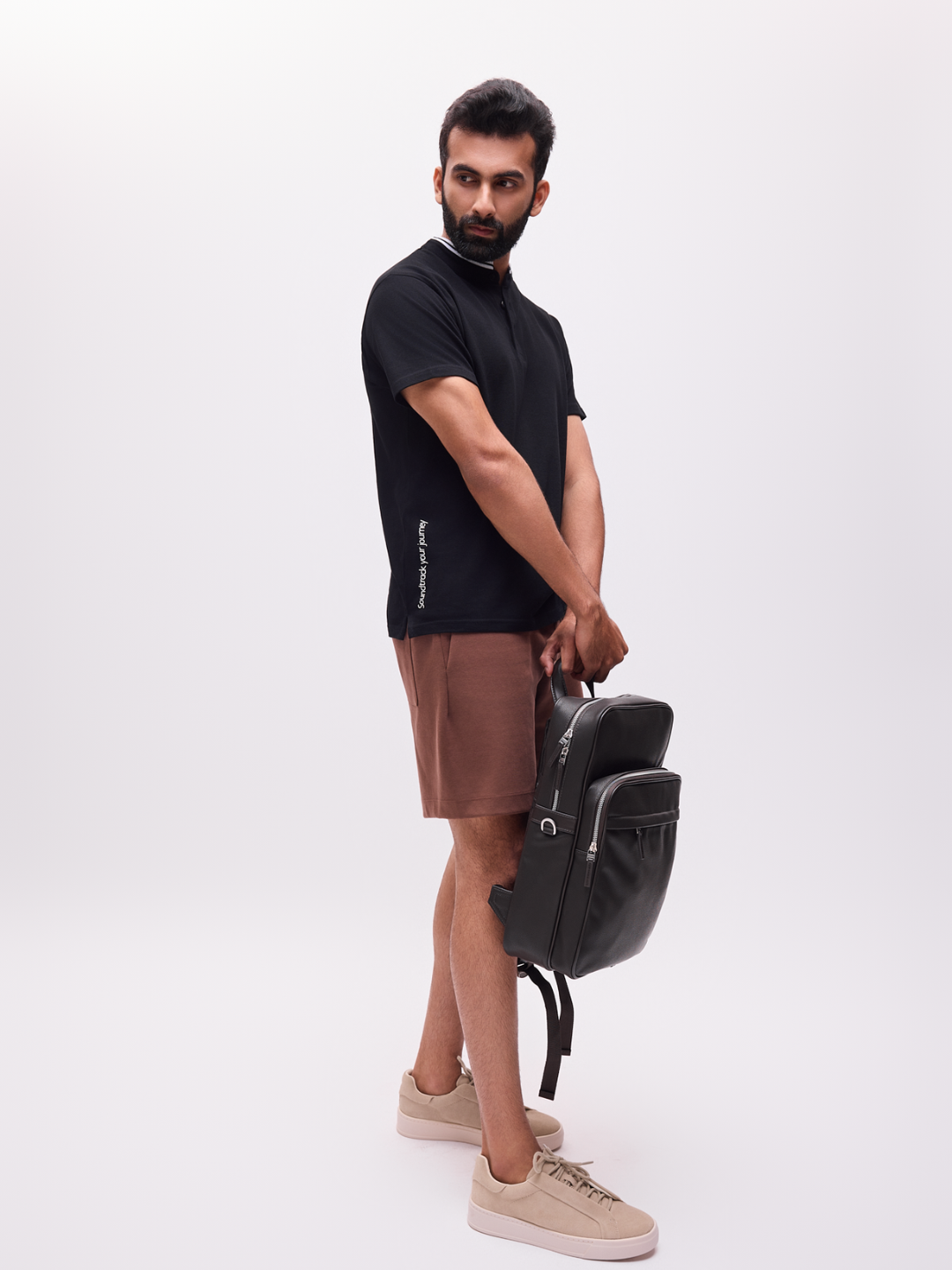 Man holding a black backpack against a white background The Groove black organic cotton tshirt